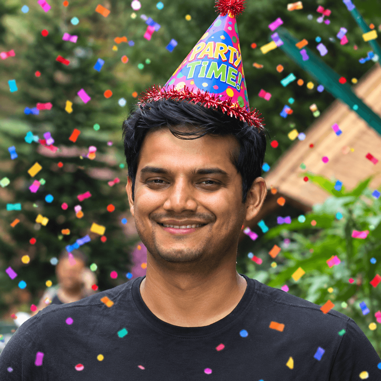Chandresh wearing a Party Time hat with confetti around him